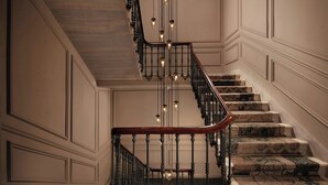 Un magnifique escalier, orné de balustrades travaillées et doté d’une main courante en bois, menant à l’étage supérieur.