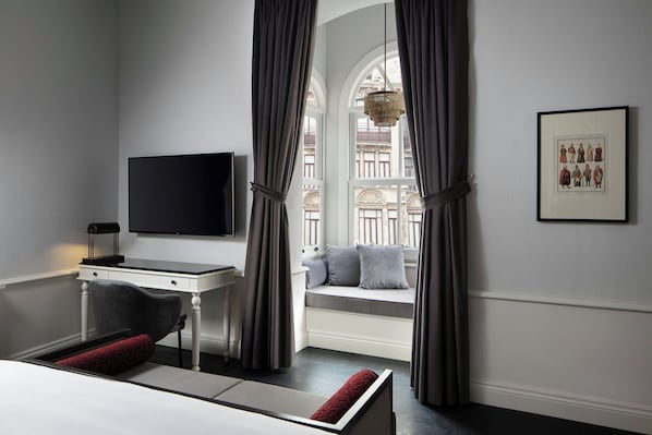 A hotel room with a bed, a desk, a television, a window with curtains, and a framed picture on the wall. - Adahan DeCamondo Pera, Autograph Collection (Istanbul)