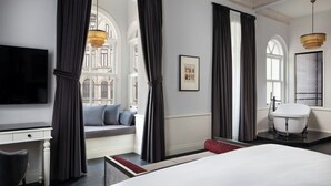 Une chambre d’hôtel moderne dotée d’un grand lit, d’un bureau, d’une baignoire et offrant une vue sur la ville.