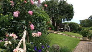 A garden with a paved walkway, a wicker basket with flowers, and a well-maintained lawn.