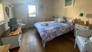 A bedroom with a bed, a desk, a chair, a window, and a picture on the wall.