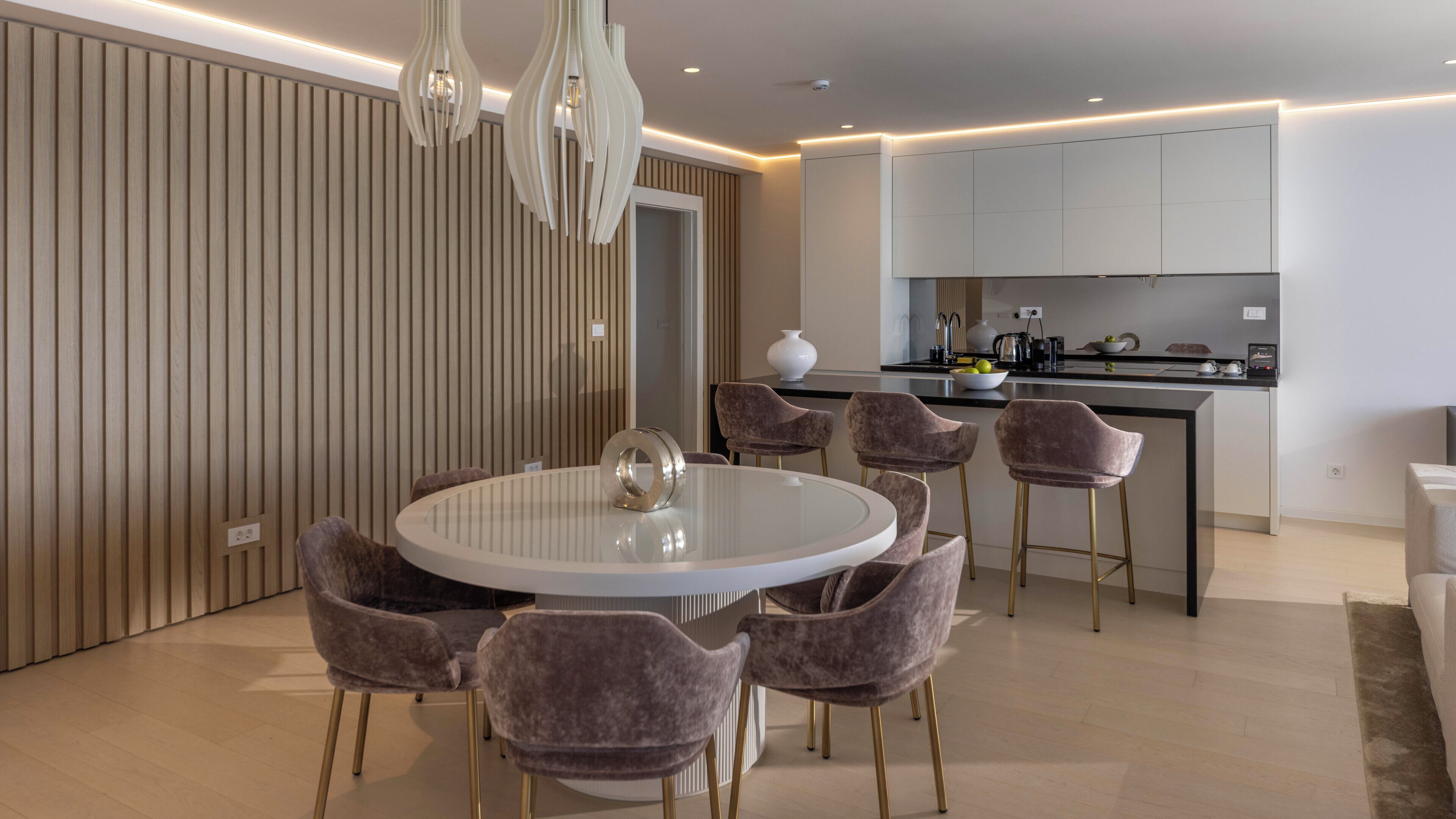 Un comedor moderno con una mesa redonda, seis sillas y una escultura decorativa de metal.