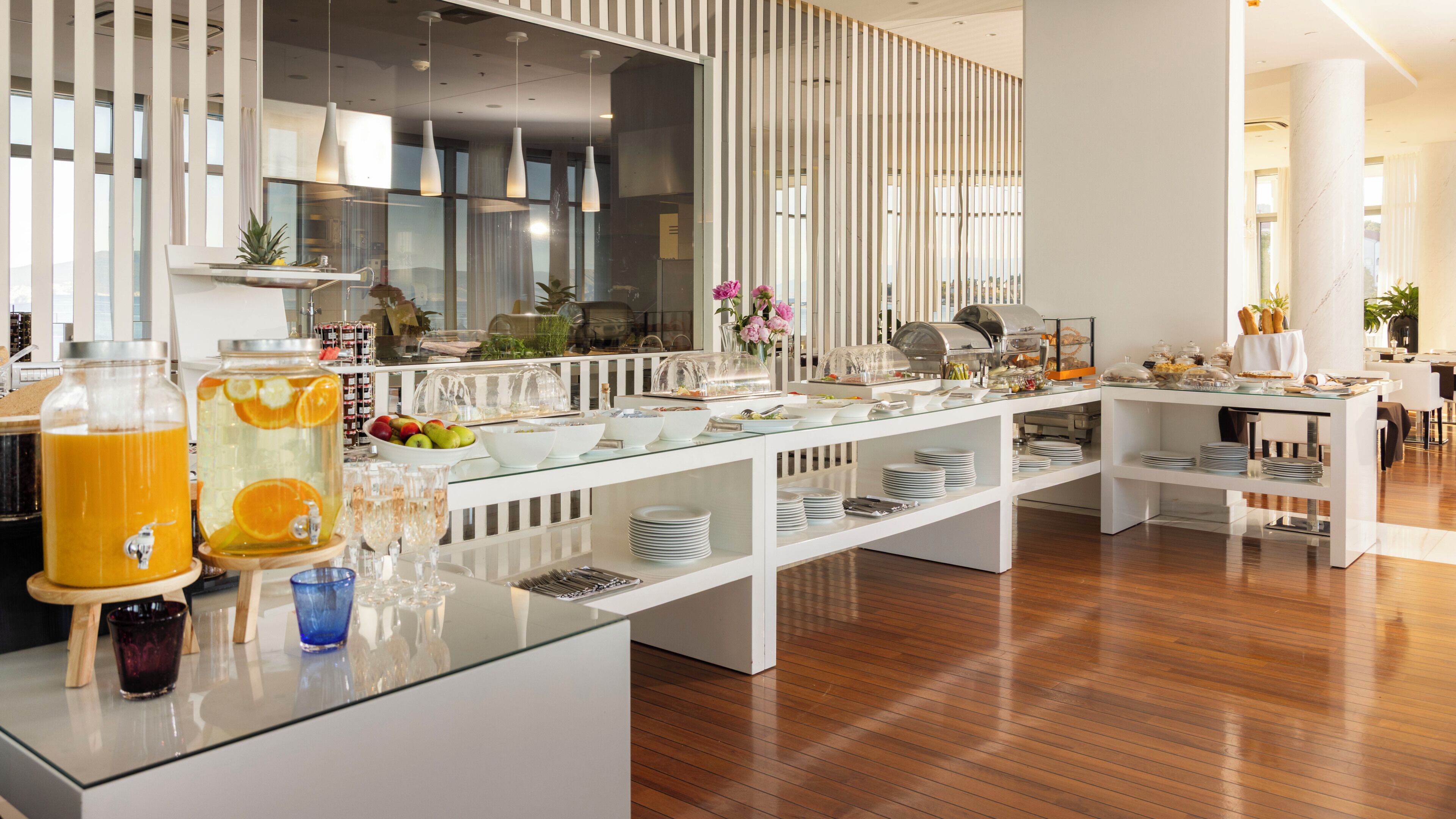 Un bufé de desayuno moderno con vitrinas de vidrio, una gran variedad de alimentos y una decoración interior limpia y contemporánea.