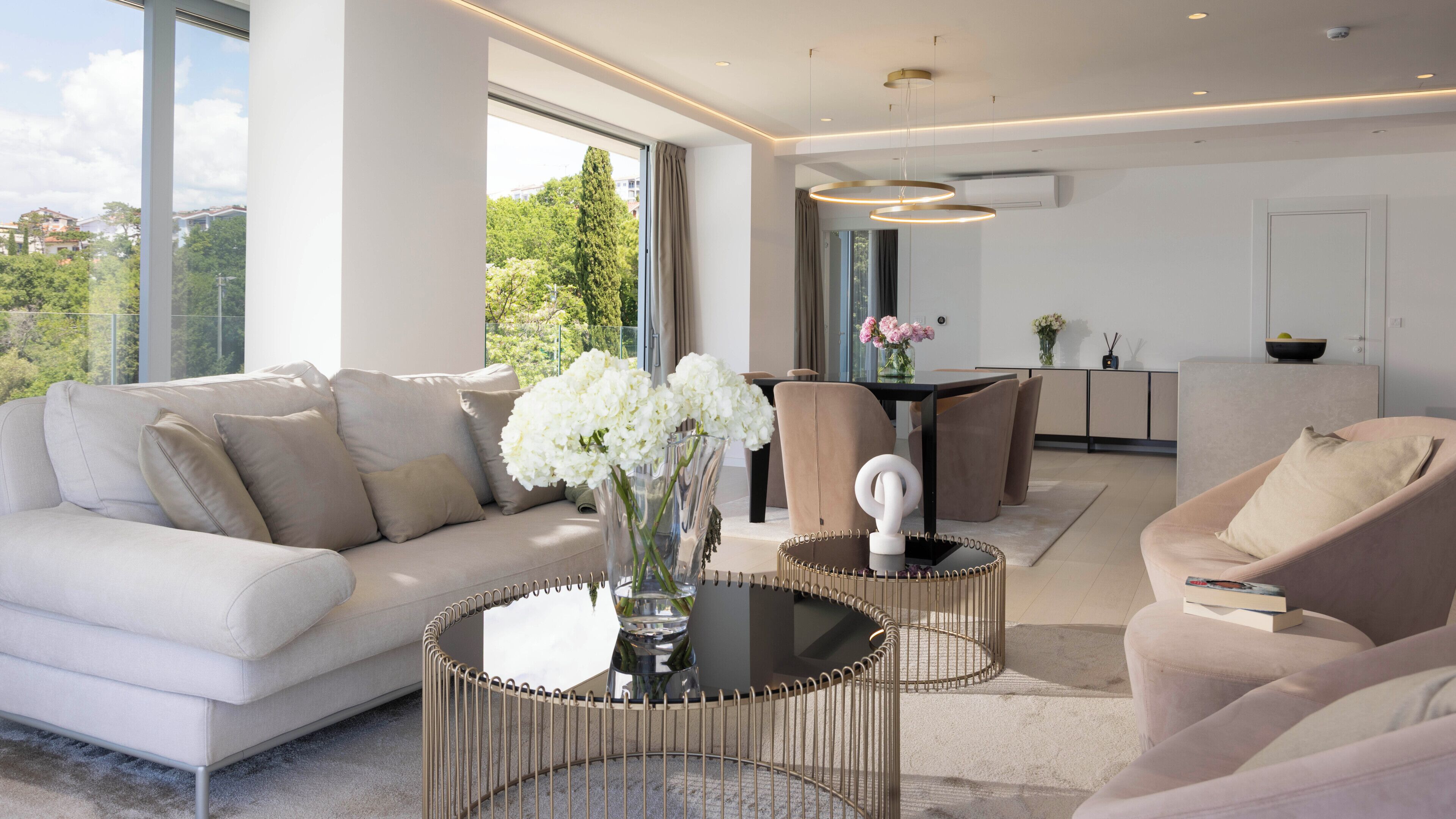 Un salon moderne avec un canapé, des fauteuils, une table à manger et une cuisine en arrière-plan.