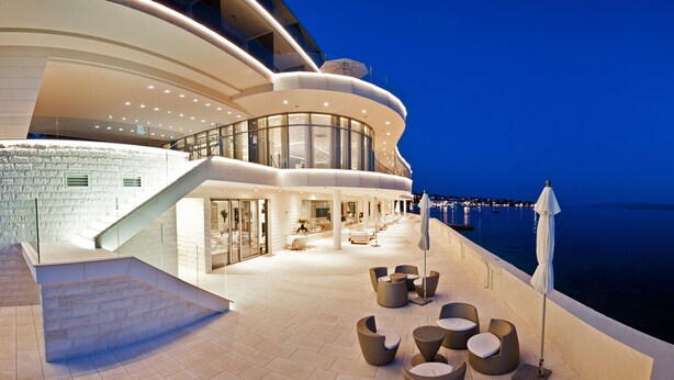 Un hôtel moderne à l’architecture extérieure incurvée, doté d’un espace extérieur aménagé et offrant une vue sur la mer.