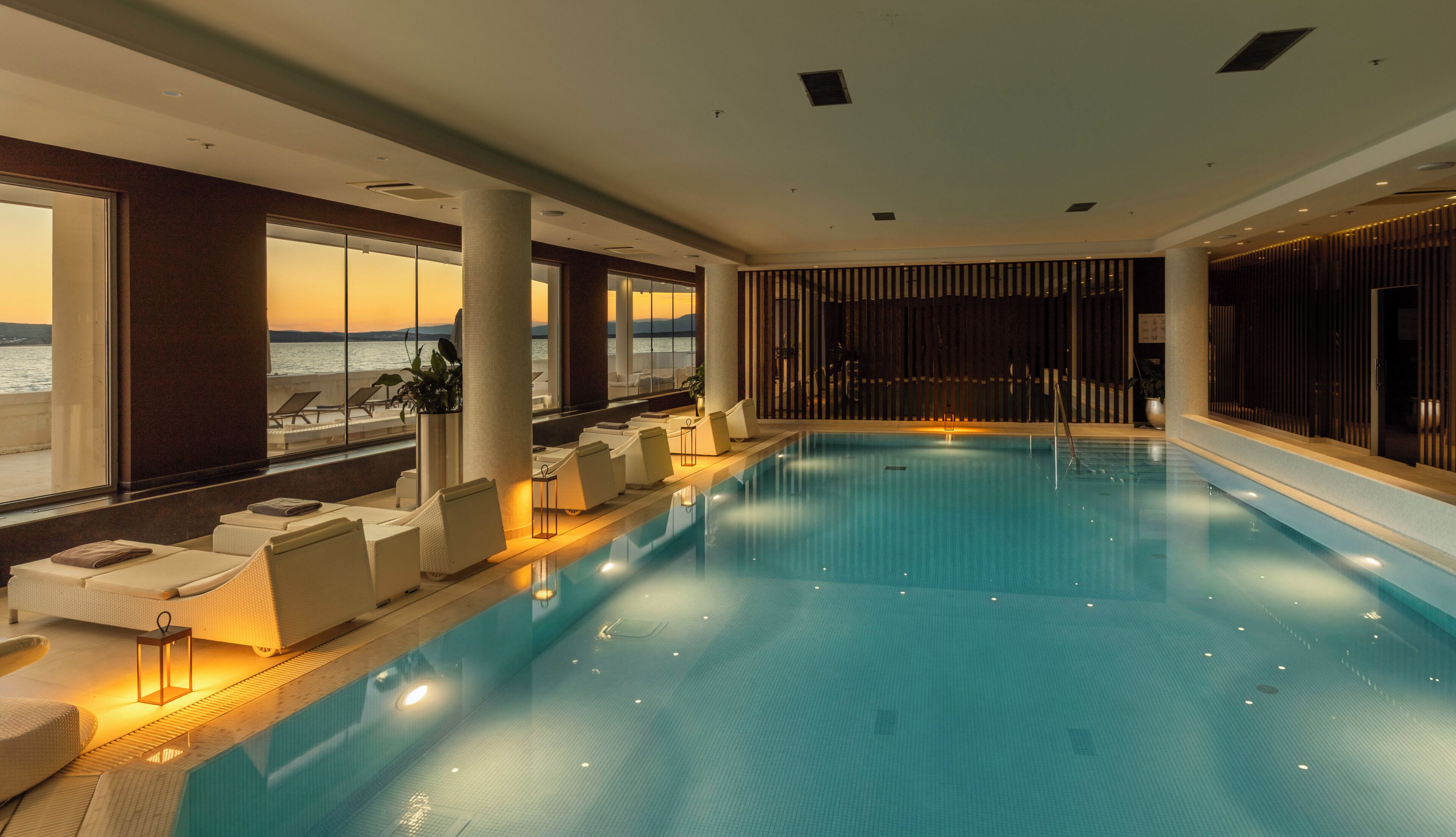 Ein Swimmingpool mit Liegestühlen und Blick auf das Meer.