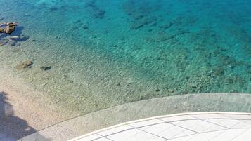 Vista despejada de una playa con piso de vidrio que permite ver el lecho marino.