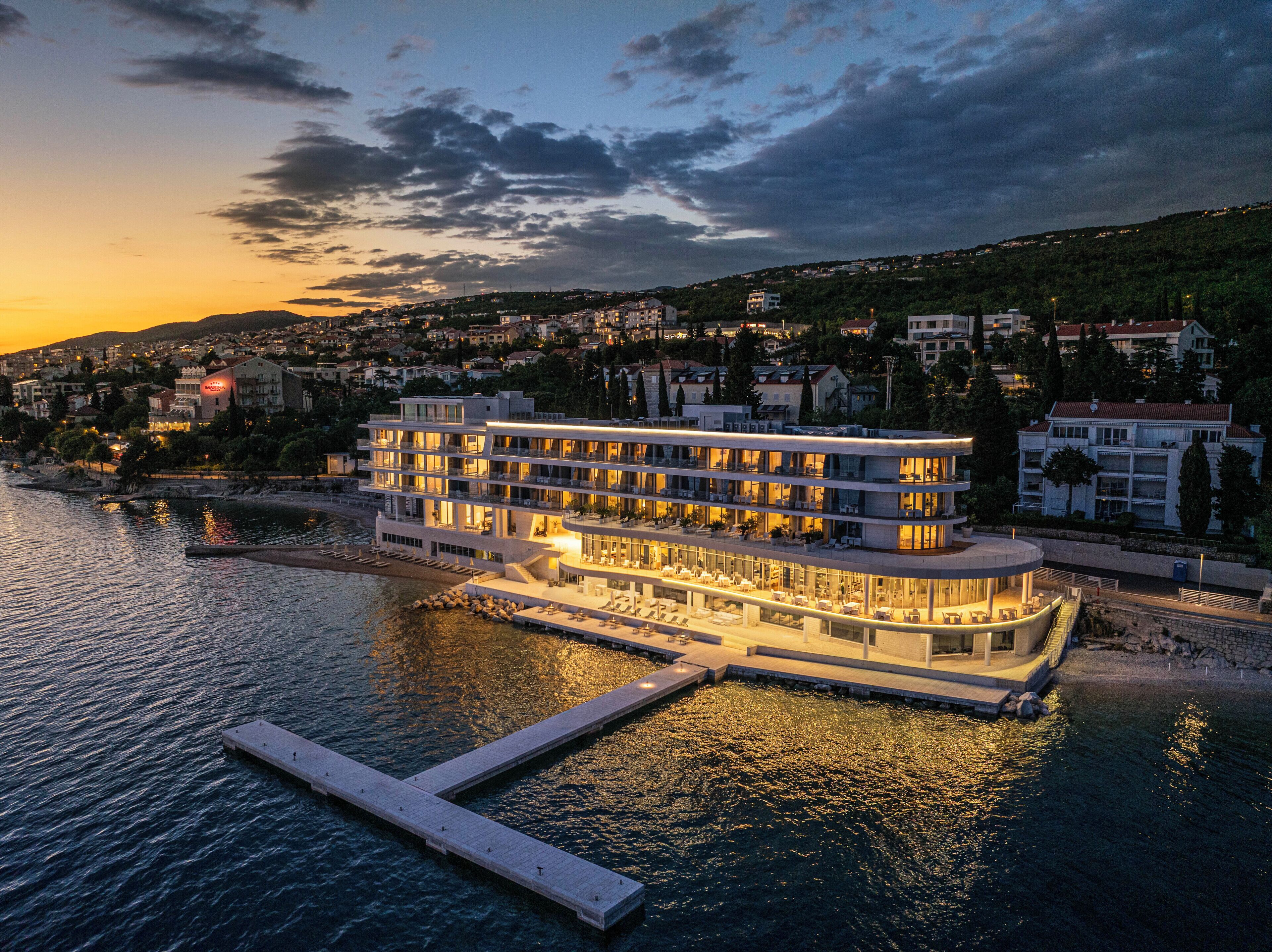 Hotel frente al agua con varios balcones, un muelle y vistas a la ciudad.