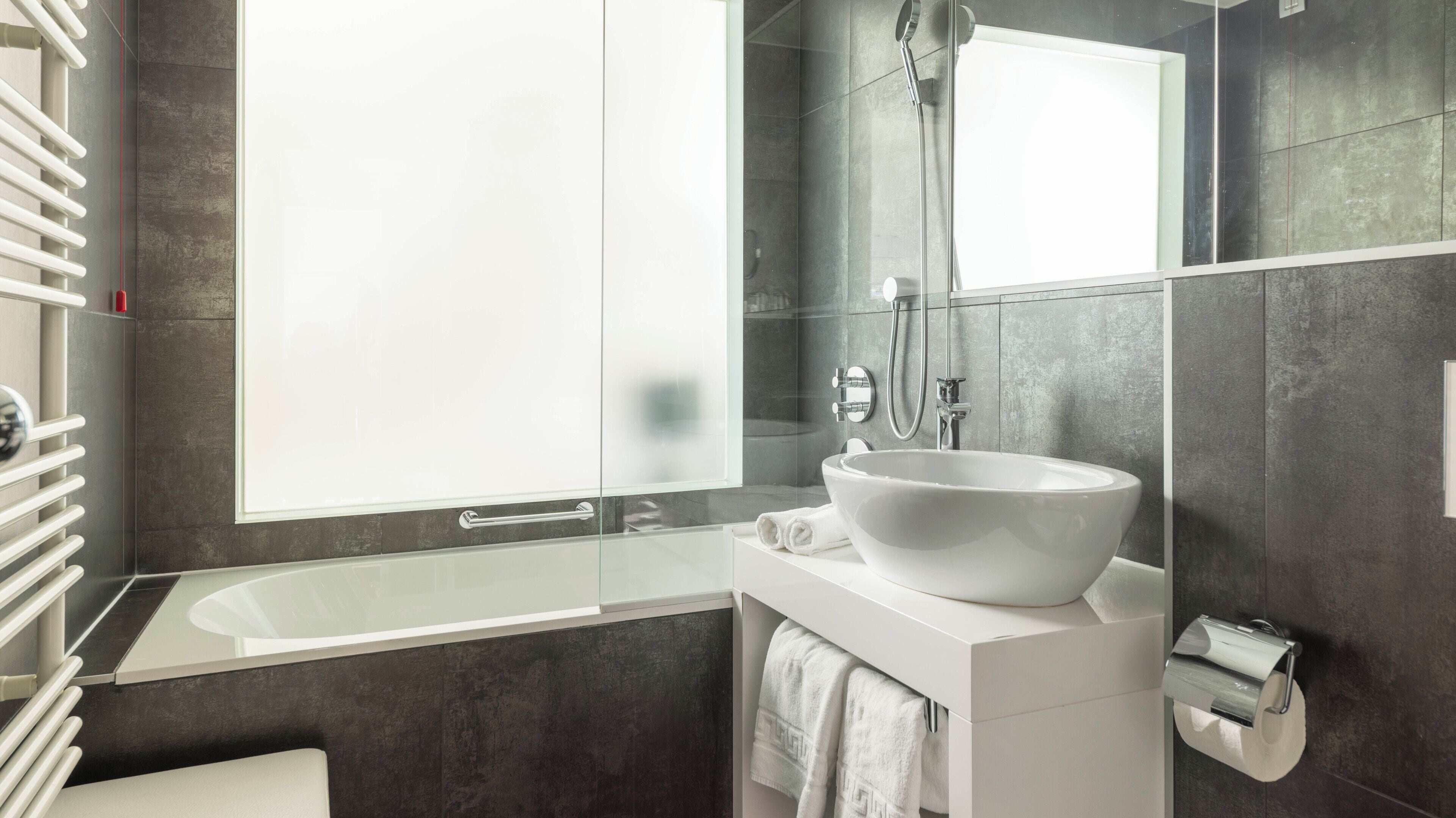 A modern bathroom with a large bathtub, a white sink, and a glass shower enclosure.
