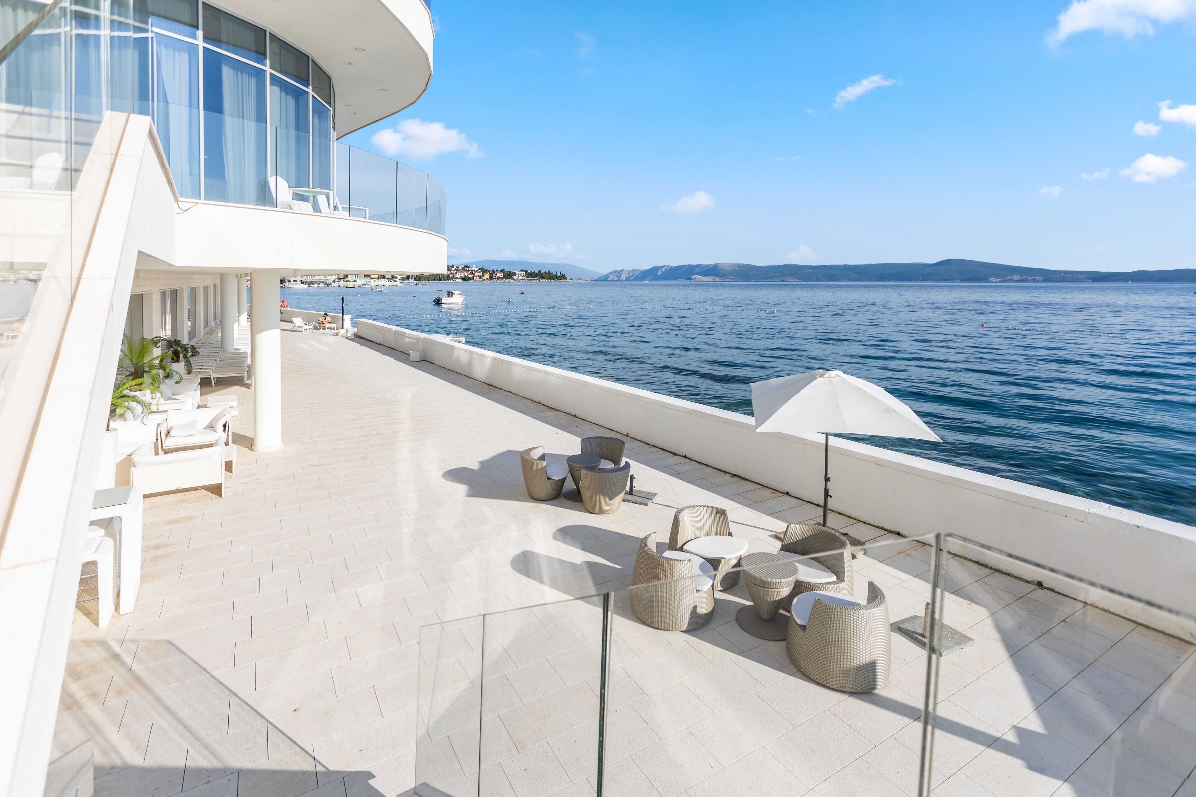 A modern outdoor deck with seating and a view of the sea.