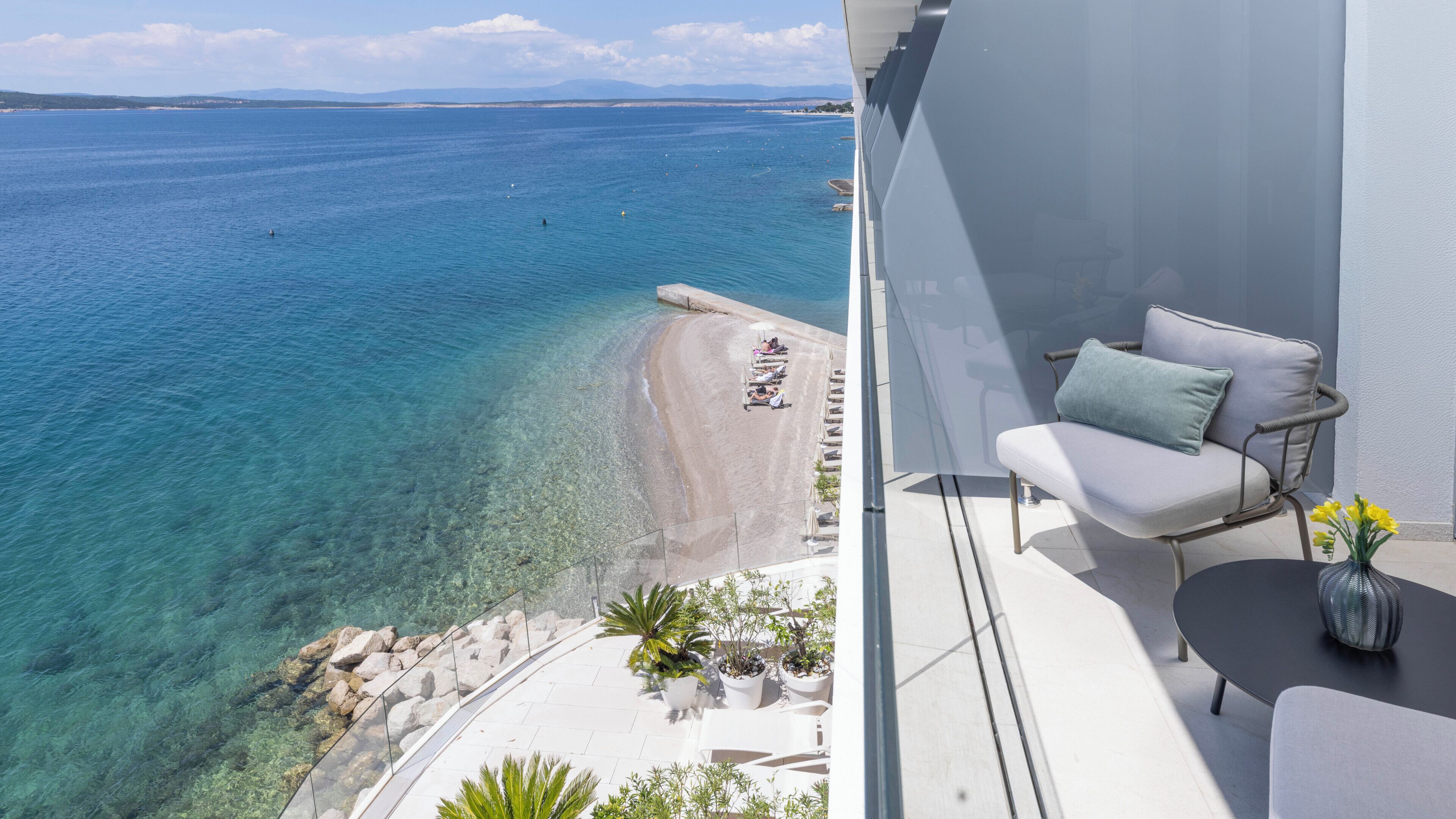 A balcony with a view of a beach and the sea.