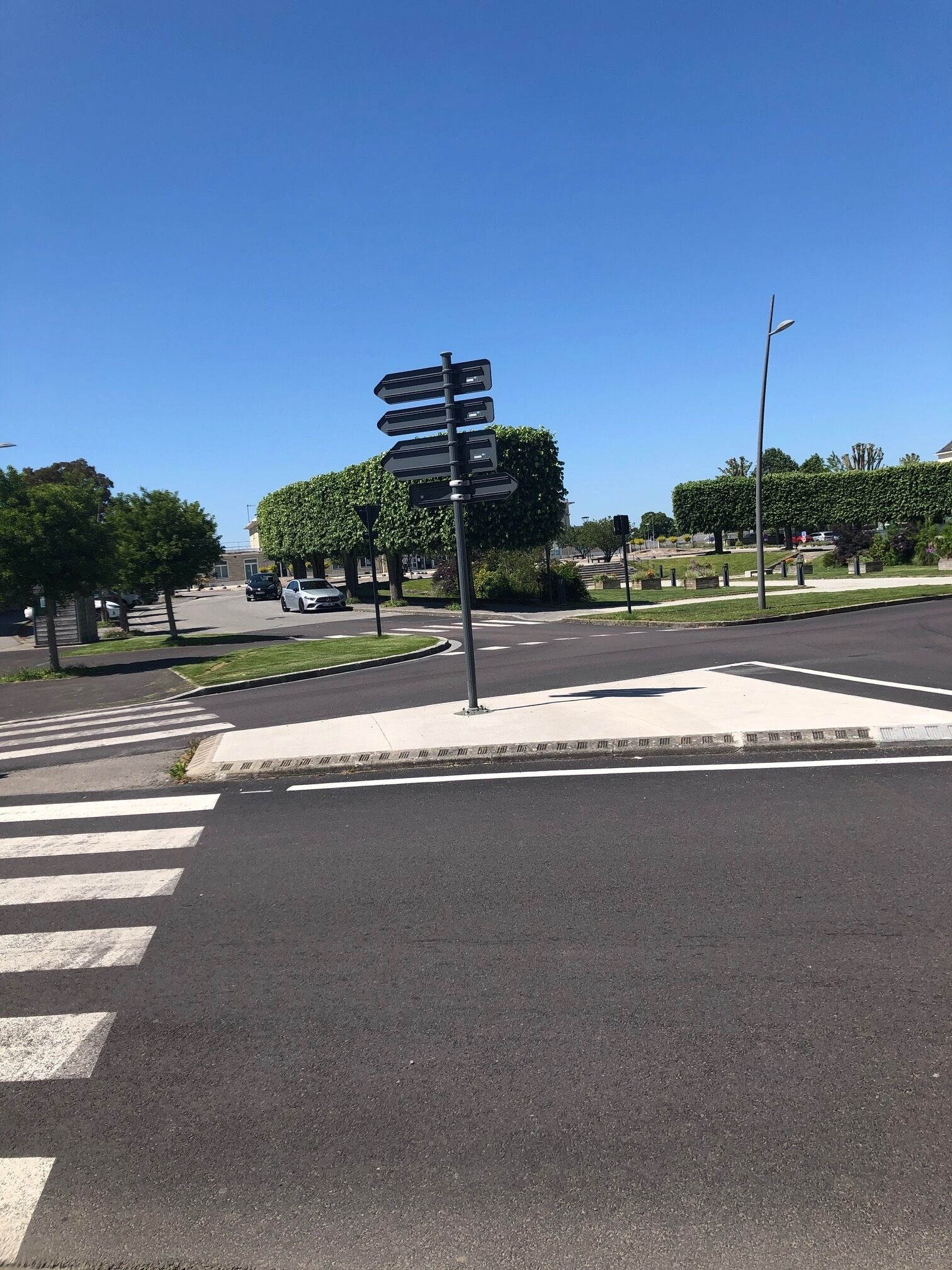 A street intersection with a directional signpost, crosswalk, and a clear blue sky.