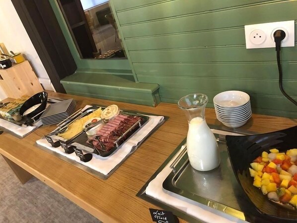 Un bufé de desayuno con diferentes opciones de comida y una jarra de leche.