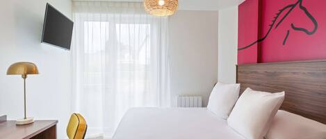 Una habitación de hotel con una cama, un escritorio, una silla, un televisor y una pared con un mural de un caballo.