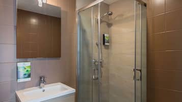 A modern bathroom with a glass-enclosed shower, a white sink, and a mirror above it.