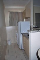 A compact kitchen with a refrigerator, a sink, and a countertop.