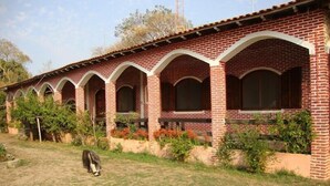 A row of brick buildings with arched windows and a grassy area in front.