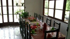 A dining area with a long table, chairs, and a tiled floor.