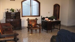 A room with a wooden chair, a desk, and a large window.