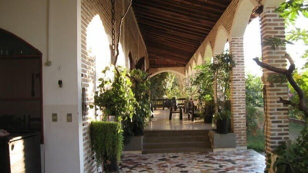 A covered outdoor area with a patterned tile floor, brick walls, and arches.
