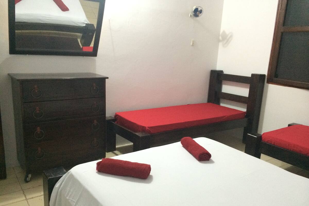 Une chambre avec deux lits simples, une commode en bois et un miroir au mur.