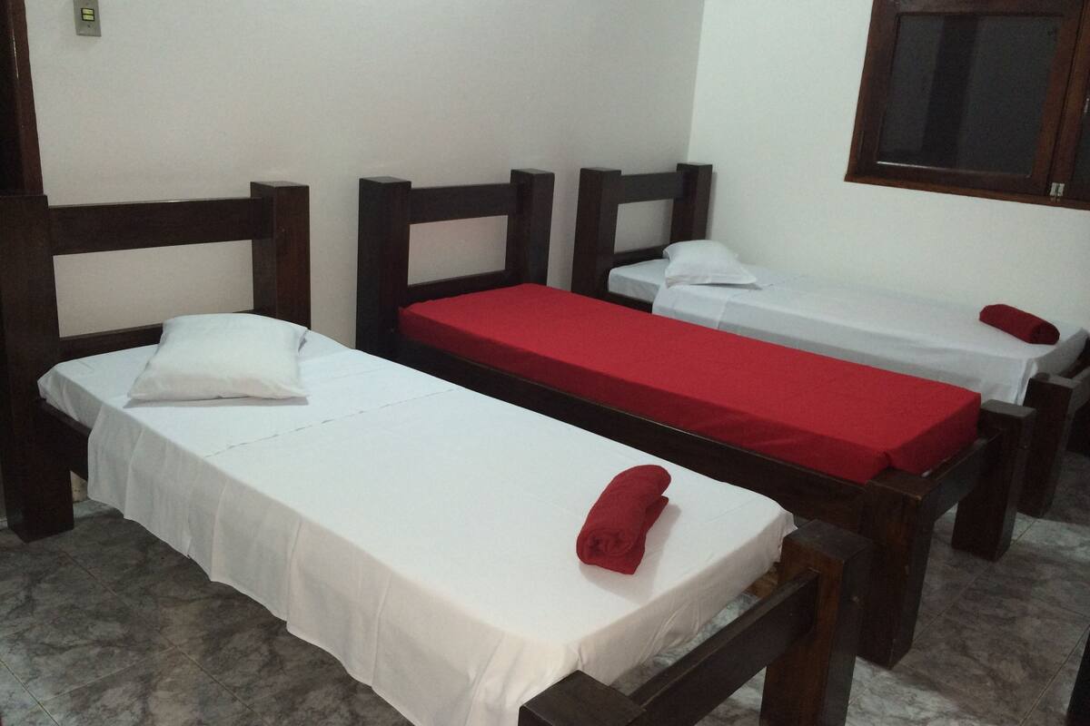 Une chambre avec deux lits simples, chacun doté d’une tête de lit en bois et de linge de lit blanc.