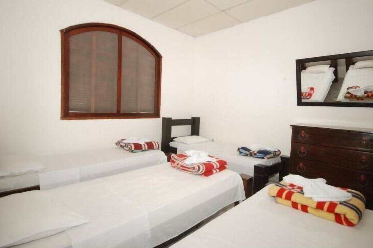 Une chambre d’hôtel avec deux lits simples, une tête de lit en bois, une commode et un grand miroir.