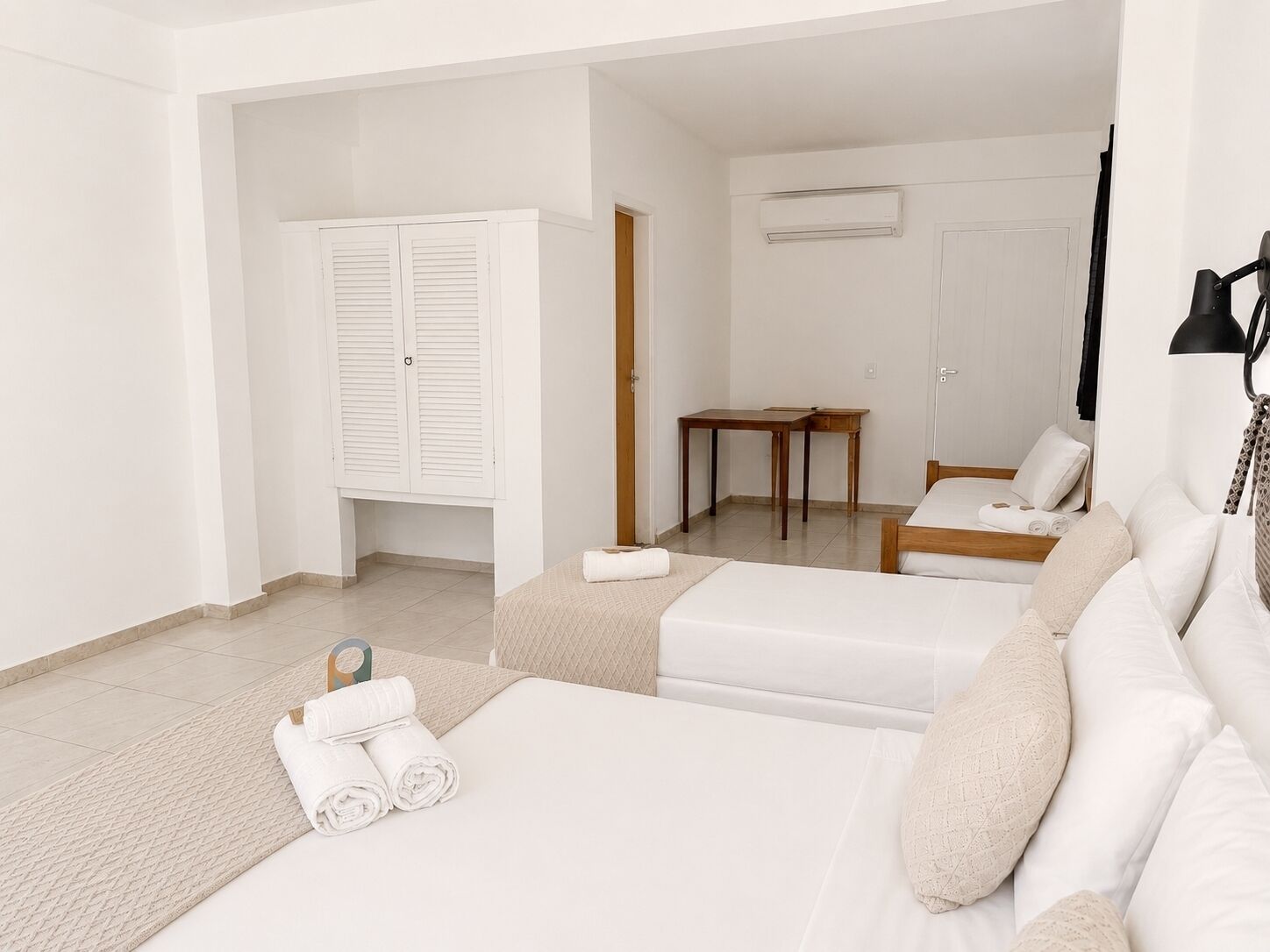 Quarto de hotel com cama, área de estar com mesa e guarda-roupa.