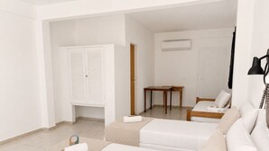 Quarto de hotel com cama, área de estar com mesa e guarda-roupa.