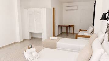 Quarto de hotel com cama, área de estar com mesa e guarda-roupa.