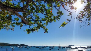 A wooden pier extending into clear blue water with boats anchored in the distance. - Calador Búzios Hotel (Búzios)