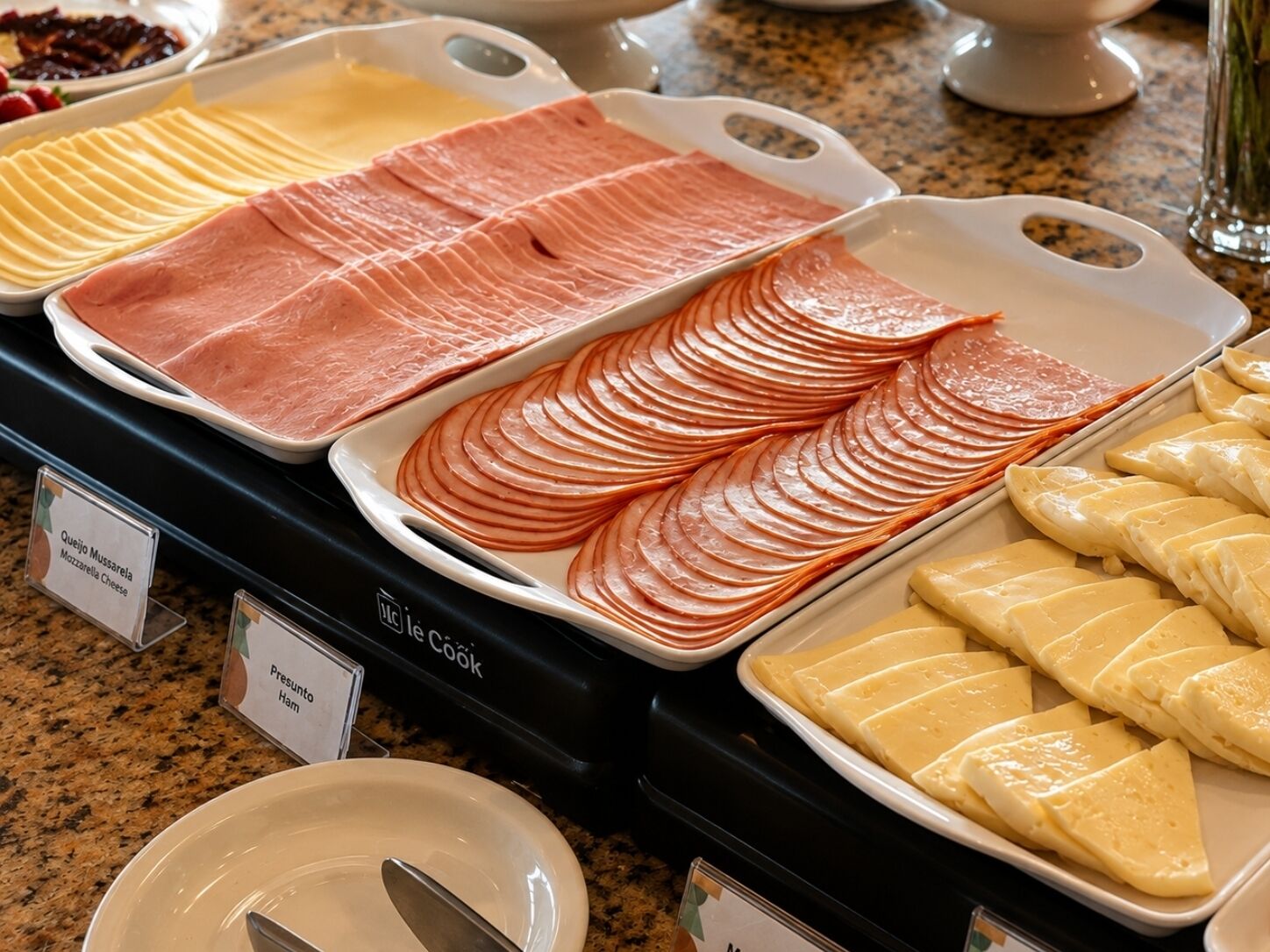 A buffet with various food items including sliced ham, cheese, and other deli offerings.