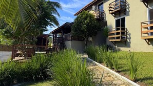 A building with a covered outdoor area, a stone pathway, and lush greenery. - Calador Búzios Hotel (Búzios)