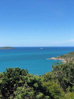 A coastal landscape with a clear view of the sea, a small island, and dense greenery in the foreground. - Calador Búzios Hotel (Búzios)