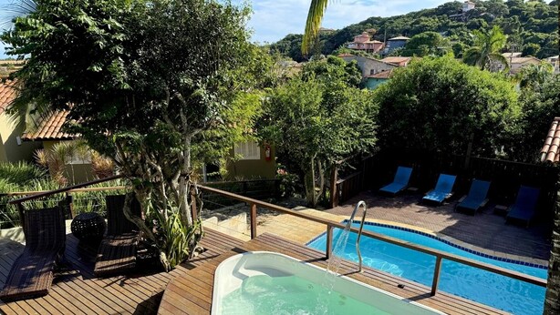 Uma piscina com hidromassagem, espreguiçadeiras e um deck de madeira.