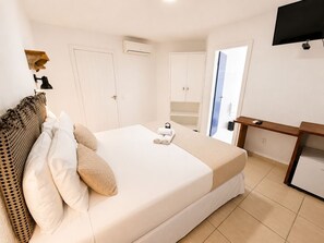 Habitació d'hotel amb llit, escriptori, televisió i armari.