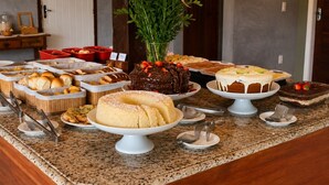 A buffet table with various food items and a decorative plant. - Calador Búzios Hotel (Búzios)