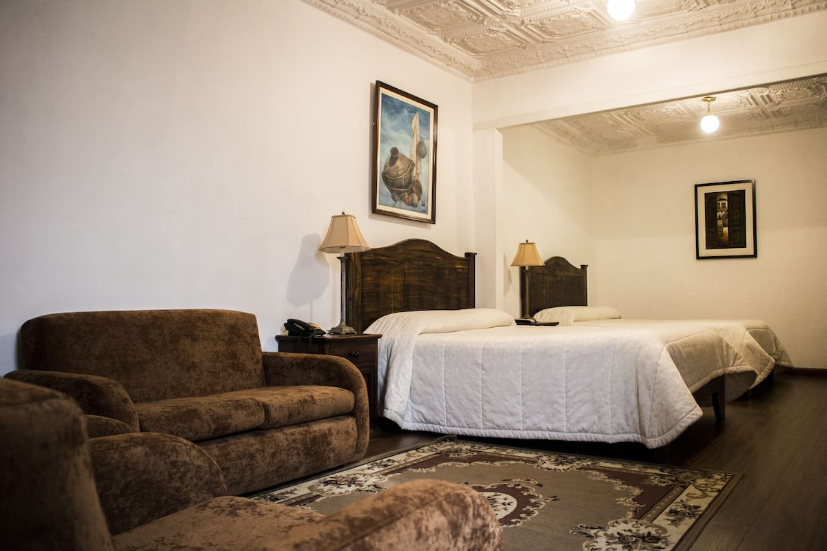 Un dormitorio con una cama grande, un sofá, una mesita de noche y un cuadro en la pared.