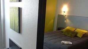 A bedroom with a bed, a nightstand, and a wall-mounted light.