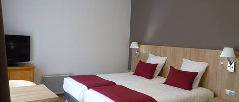 Habitación de hotel con una cama grande, dos mesitas de noche, un televisor y una pequeña mesa con sillas.