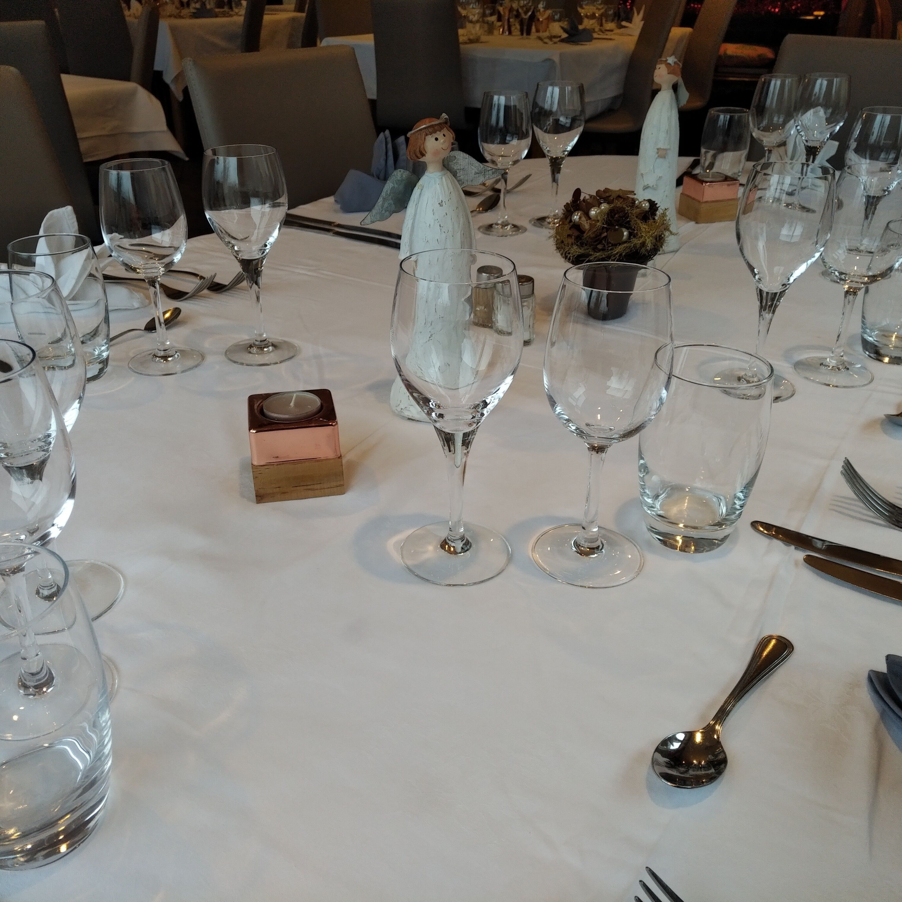 Une table à manger dressée avec plusieurs verres à vin, un petit chandelier et des couverts.