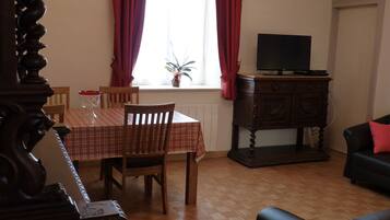 Una sala de estar con una mesa de comedor, sillas, televisor y un sofá.