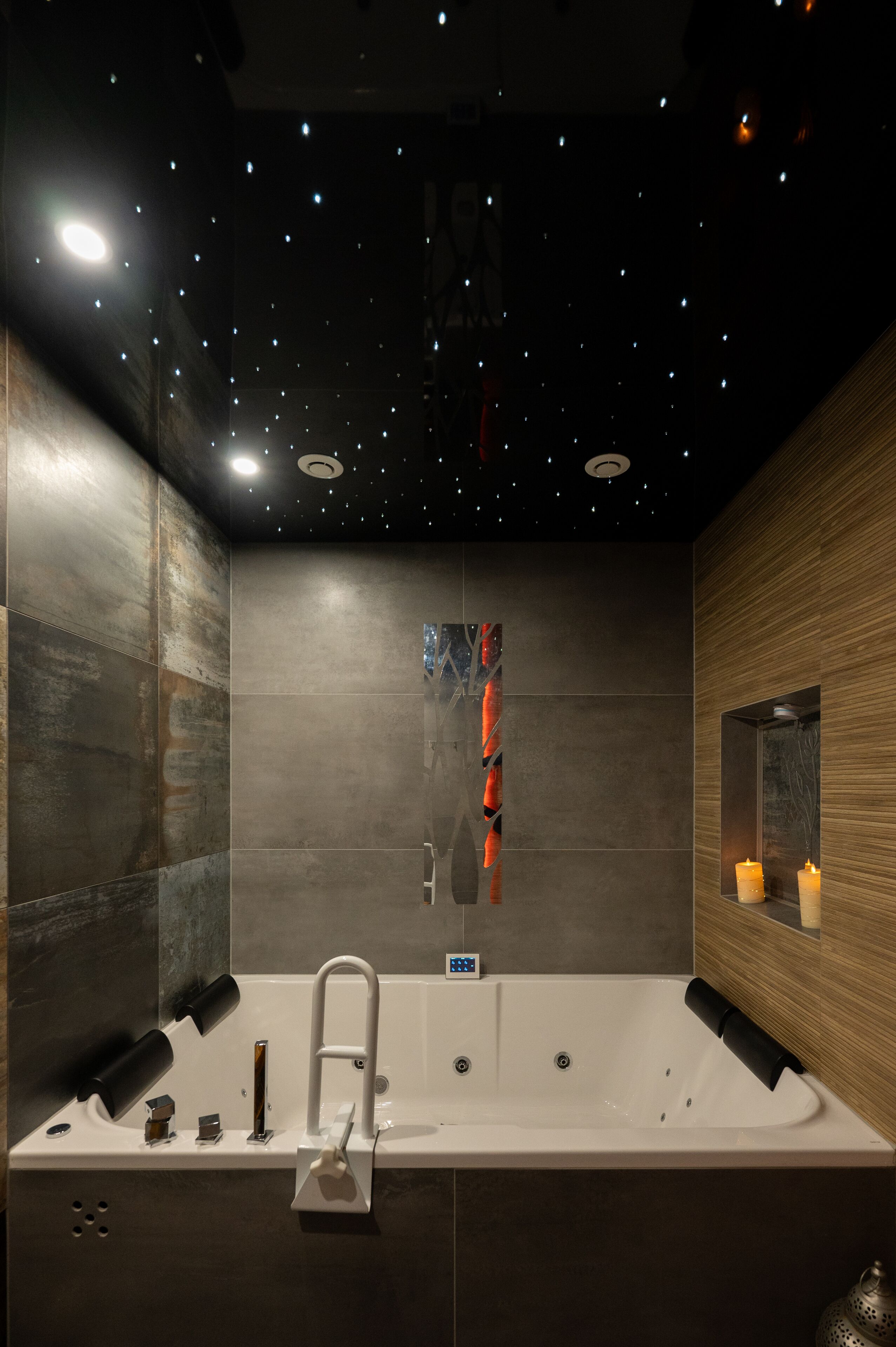 Ein modernes Badezimmer mit einer großen Badewanne, einem Spiegel und einer Decke mit Sternenmuster.