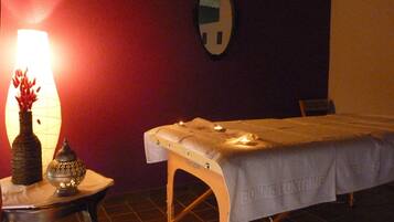 A room with a massage table, a lamp, and a decorative vase on a small table.