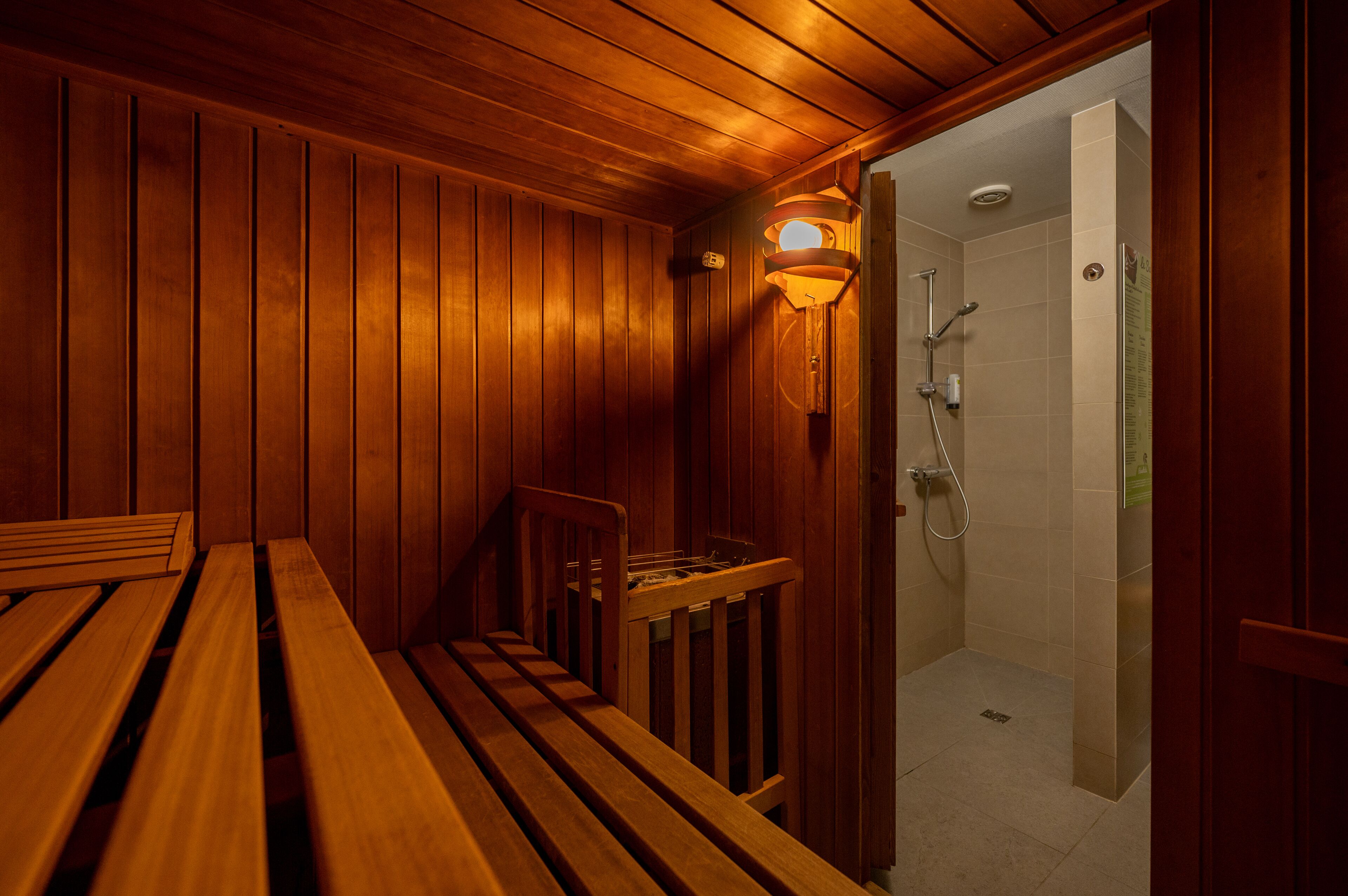 Een houten sauna met banken en een douchegedeelte.