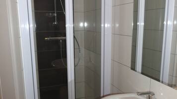 Un baño con ducha vidriada, lavamanos y espejo.