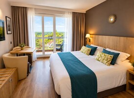 Una habitación de hotel con una cama grande, un escritorio y un balcón con vistas.