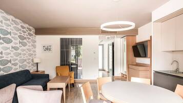 Una sala de estar moderna con un sofá, sillas, una mesa y un televisor montado en un mueble de madera.