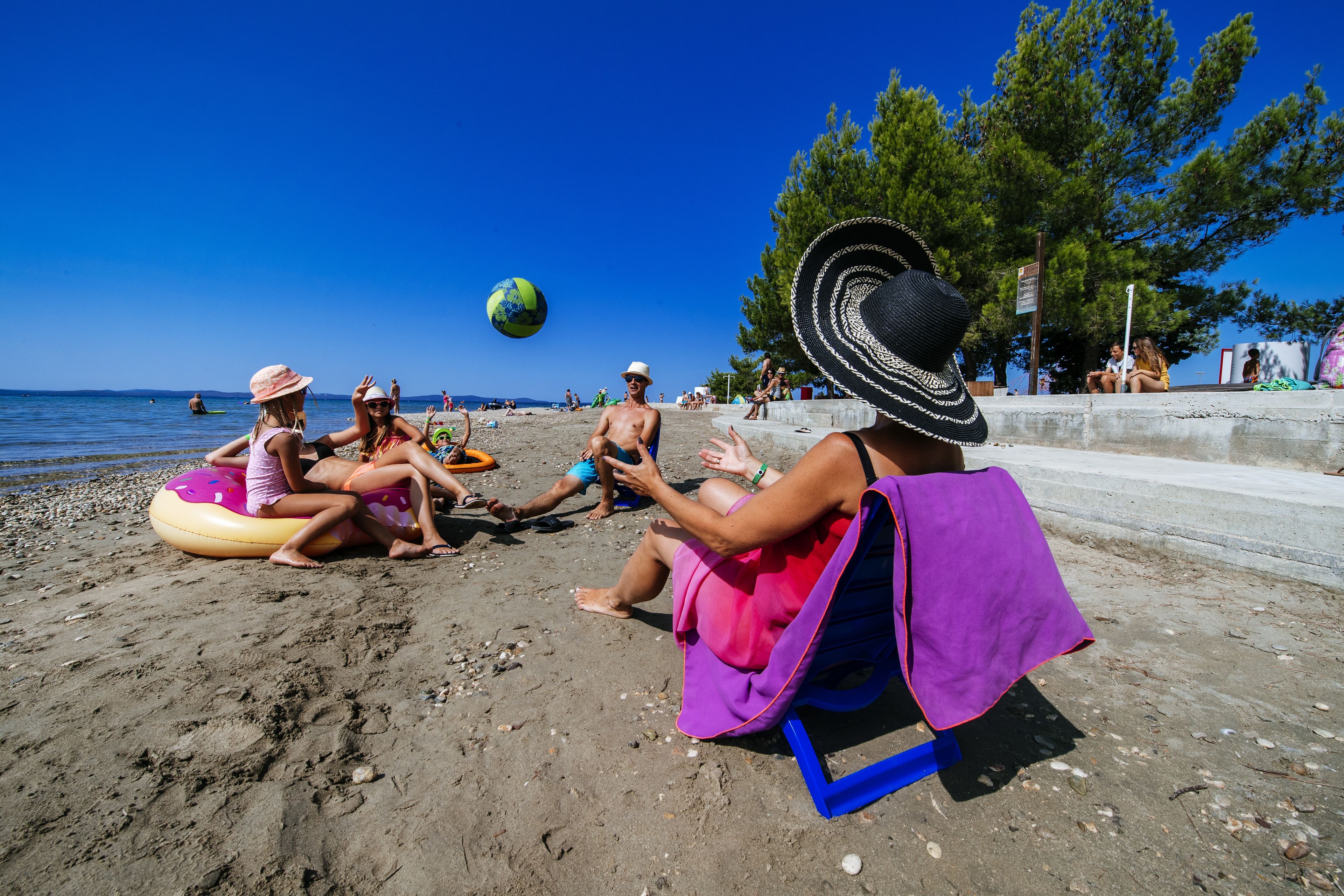 A beach scene with people sitting on chairs and inflatable tubes.
