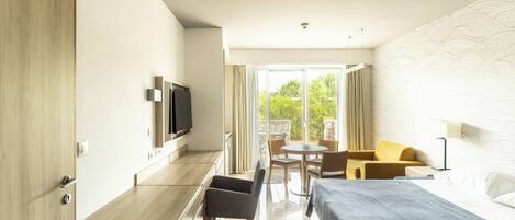 A modern hotel room with a bed, a desk, a TV, and a balcony with a table and chairs.